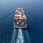 Aerial Drone Ultra Wide Photo Of Huge Container Ship Cruising Deep Blue Open Ocean Sea Near Logistics Container Terminal Port
