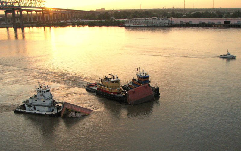 Towing vessels hold the barge DM-932 in position following a collision near New Orleans that spilled 282,000 gallons of fuel into the Lower Mississippi River.
