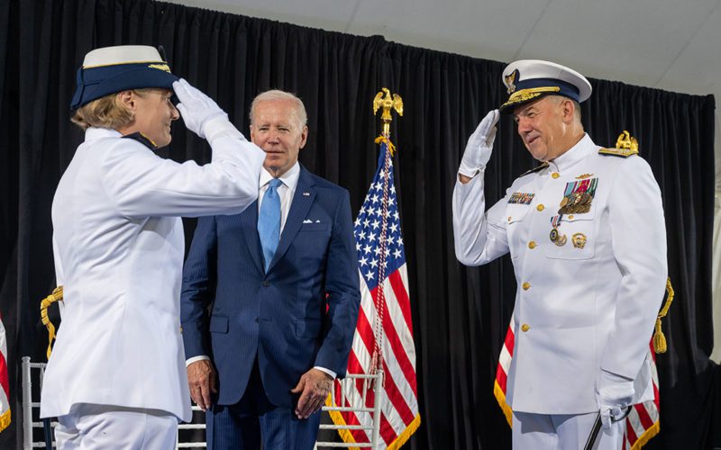 Coast Guard Commandant Adm. Linda Fagan salutes her predecessor, Adm. Karl Schultz, as President Biden looks on.