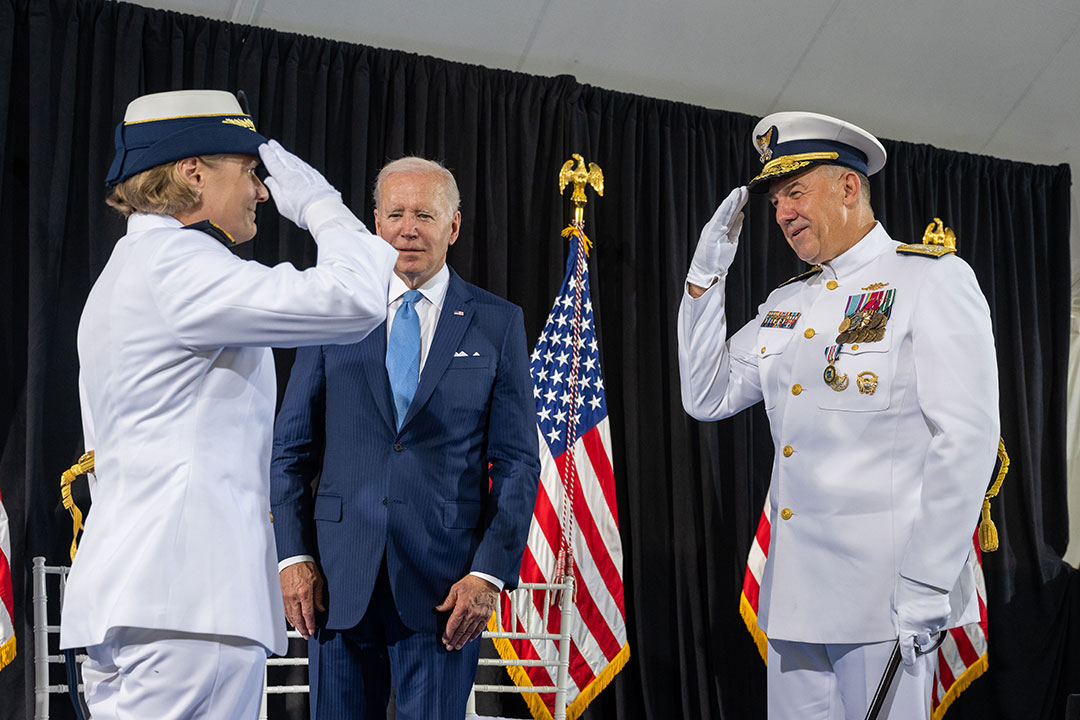 Coast Guard Commandant Adm. Linda Fagan salutes her predecessor, Adm. Karl Schultz, as President Biden looks on.