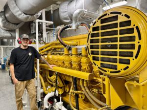 Engineer Blaine McNabb stands alongside a Cat 3516 main engine.