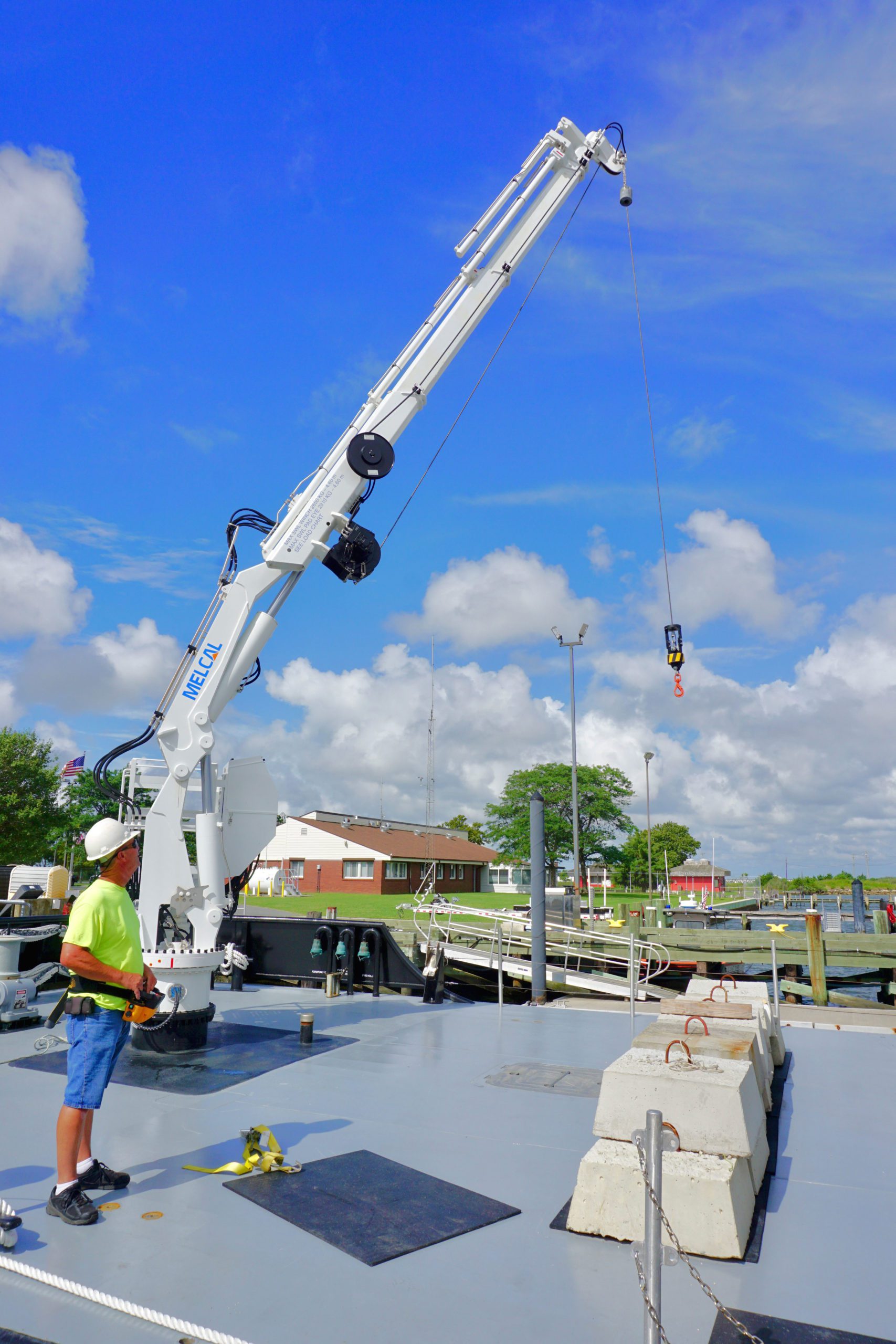 Engineer Edward Long demonstrates the Melcal crane installed on the bow, which has a 40-foot reach at full extension. The row of 900-pound cement blocks on deck are used to anchor buoys in position.