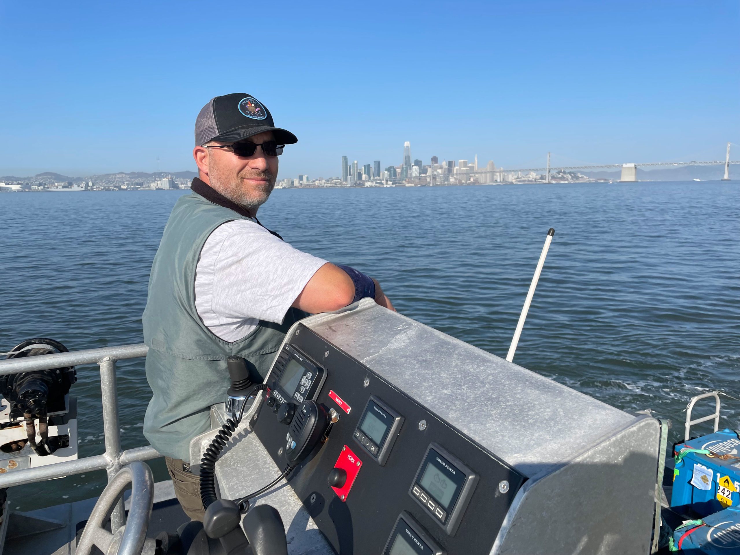 Capt. Julio Barba stands near the aft steering controls with San Francisco looming in the background.