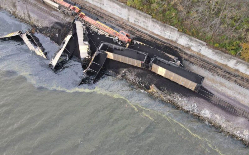 Two locomotives and 10 hopper cars derailed after the train struck the corner of a barge overhanging the rail bed along the Mississippi River.