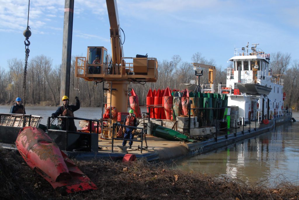 Crew aboard the Coast Guard cutter Greenbrier remove a buoy from the bank along the Mississippi River.