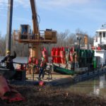Crew aboard the Coast Guard cutter Greenbrier remove a buoy from the bank along the Mississippi River.