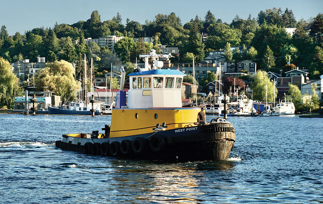 Western Towboat tug West Point underway in the Lake Washington Ship Canal in Seattle as the late summer sun sets.