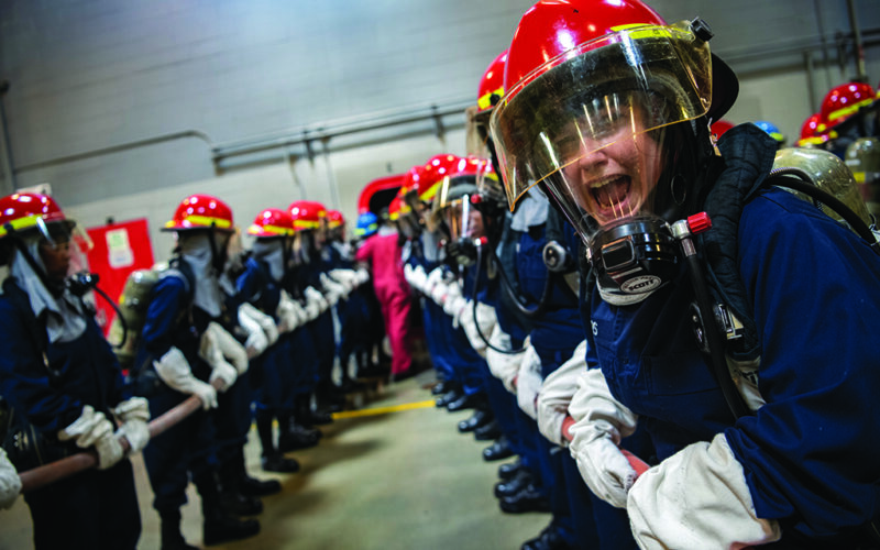 Recruits participate in firefighting and damage-control training inside the USS Chief Fire Fighter Trainer at Recruit Training Command. While firefighting remains a cornerstone of mariner training, new technologies — including AI-assisted detection systems, aerosol suppressants and specialized protections against lithium-ion battery fires — are reshaping how the maritime industry prepares for shipboard emergencies.