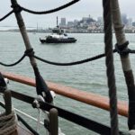 The Crowley tug Apollo stands by as the U.S. Coast Guard Barque Eagle enters San Francisco Bay on a cold, foggy morning in June 2025.