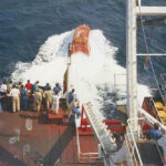 A free-fall lifeboat hits the water during a launch. The U.S. Coast Guard is urging vessel operators to closely inspect aging fiberglass lifeboats, particularly high-stress and load-bearing areas.
